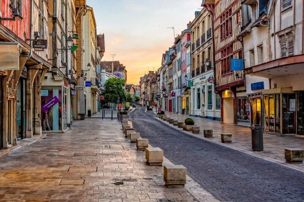 Rue piétonne du centre-ville de Troyes au coucher du soleil, bordée de maisons à pans de bois et de commerces